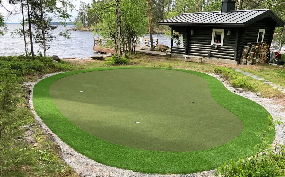 Tekonurmiviheriö mökin rannassa saunan vieressä.