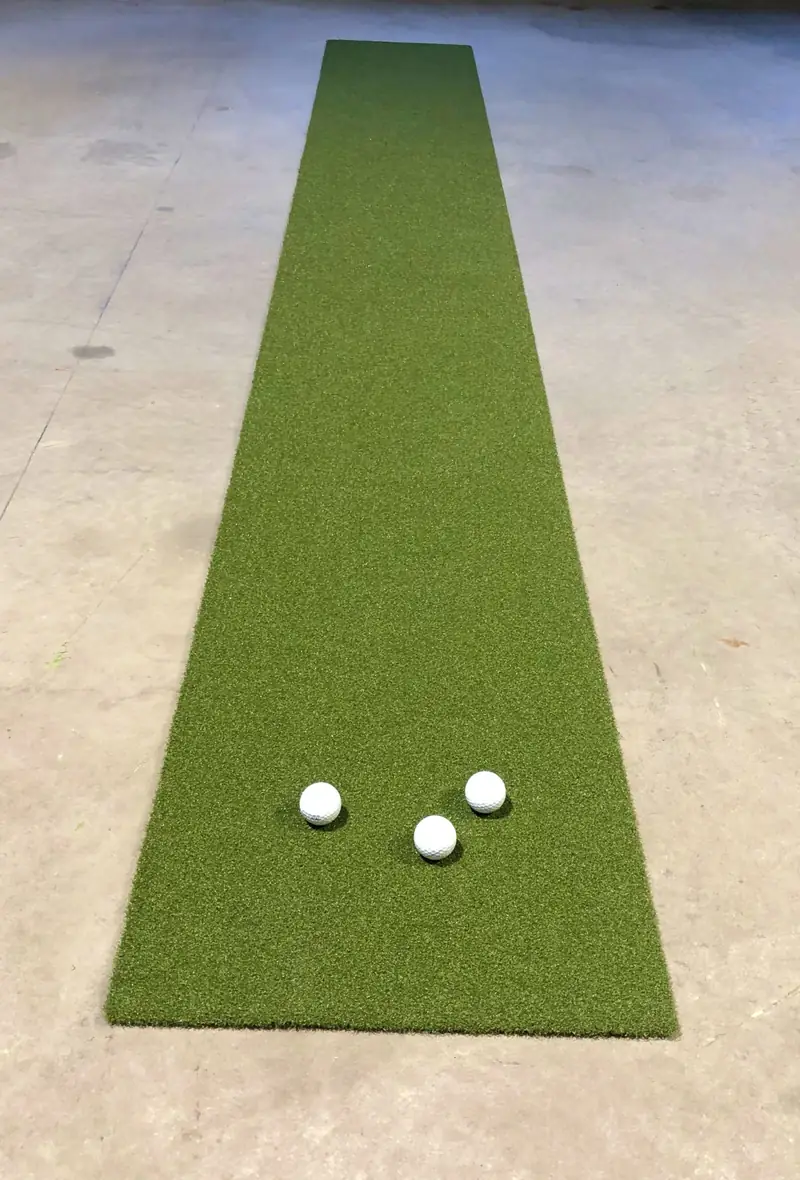 Kapea puttimatto ja kolme golfpalloa betonilattialla.