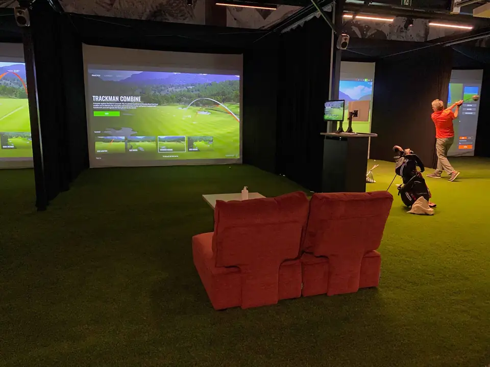 Trackman-simulaattorikoppi, lattiassa lyönti- ja puttinurmi.
