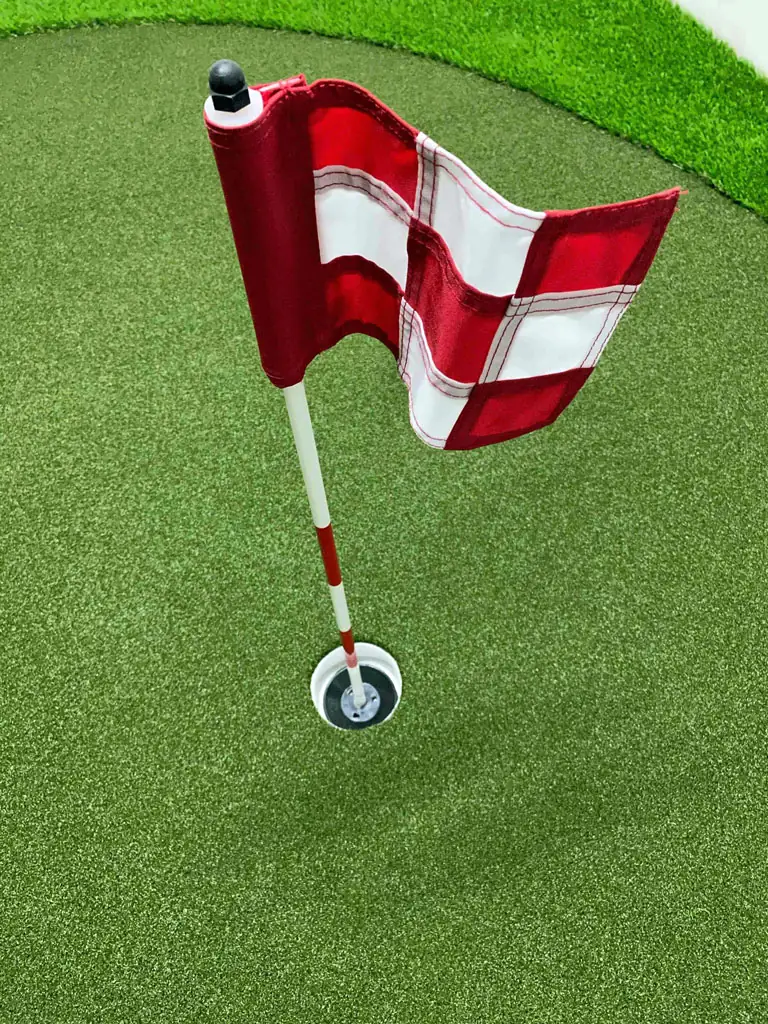 Punavalkoinen Par Aide -viheriölippu tekonurmiviheriöllä.