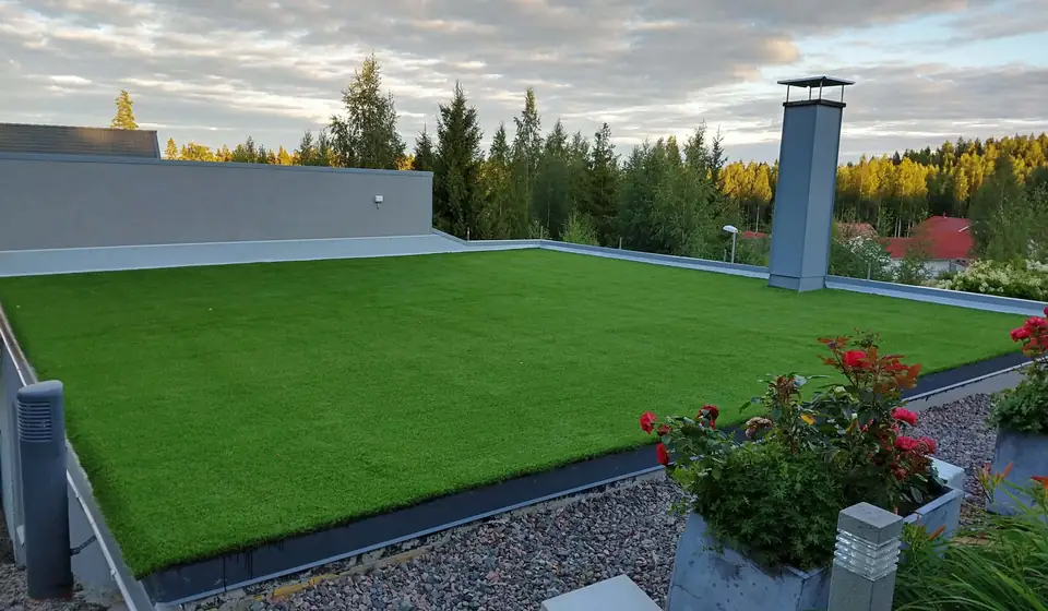 Tekonurmi kattoterassilla, reunalla ruusuja ruukuissa.