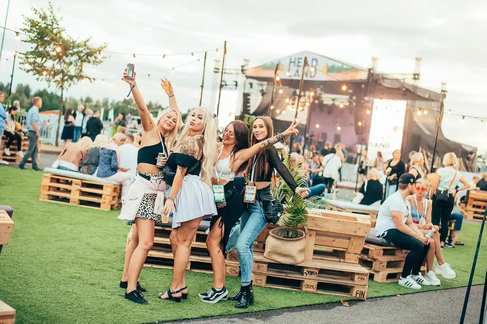 Festivaalin oleskelualue tekonurmella, kuormalavasohvia ja lavan valot taustalla.
