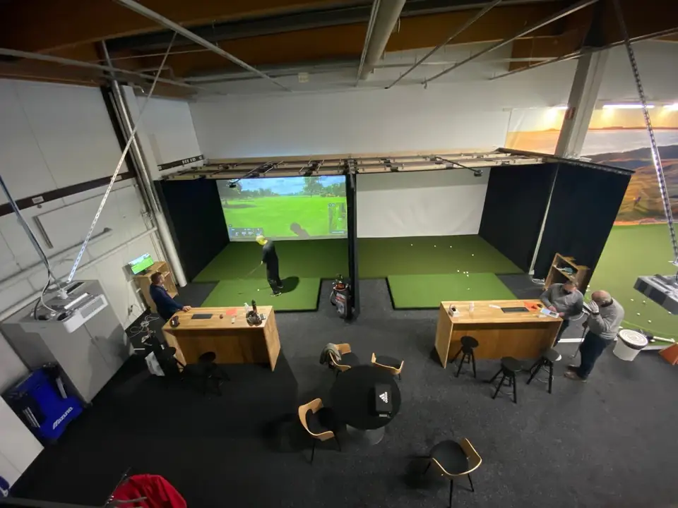 Golfhallin simulaattoripaikat, lyöntimatot ja valkokankaat ylhäältä kuvattuna.